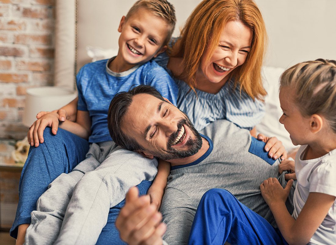 Personal Insurance - A Happy Family Having Fun Together and Relaxing at Home While Wearing Pajamas