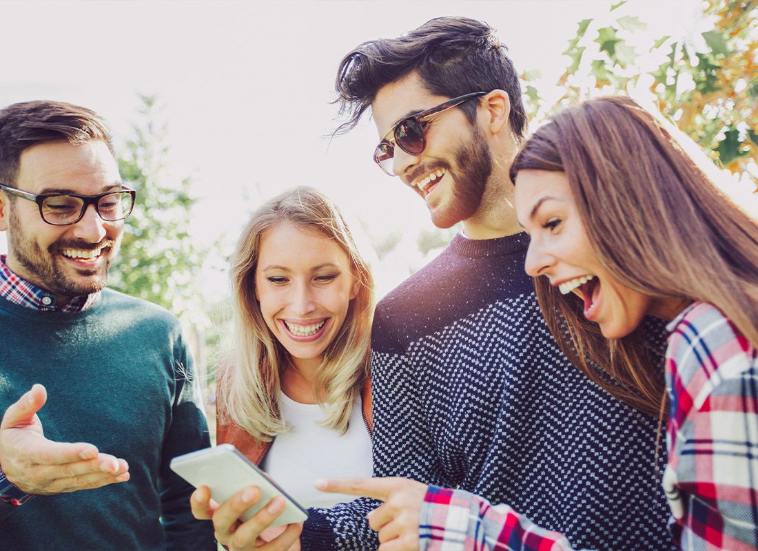 Read Our Reviews - A Group of Friends Smiling at a Smartphone and Pointing at it